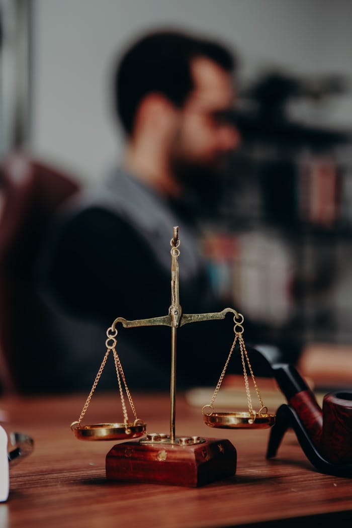 Close-up of justice scales and pipe on a lawyer's desk, emphasizing legal themes.